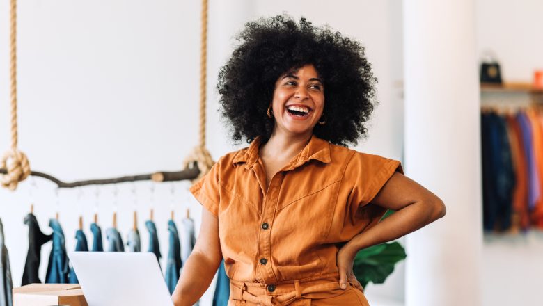 Ethnic small business owner smiling cheerfully while standing in her shop.